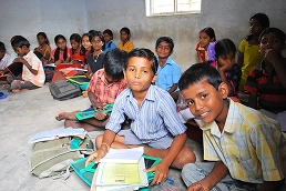 Schoolchildren seated on the floor of a rural classroom