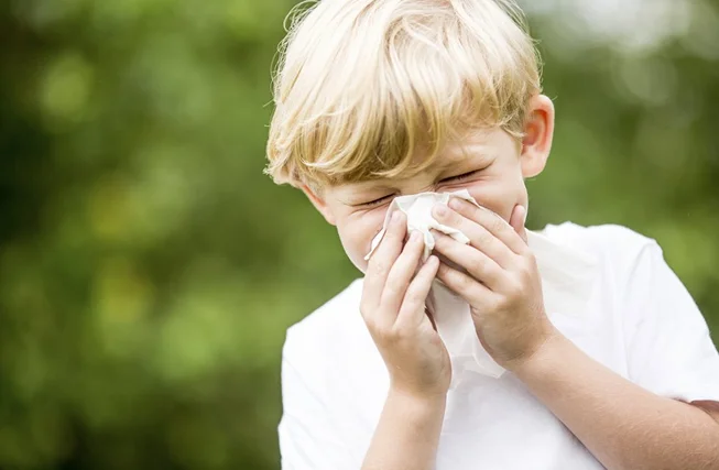 A child covering their face while sneezing