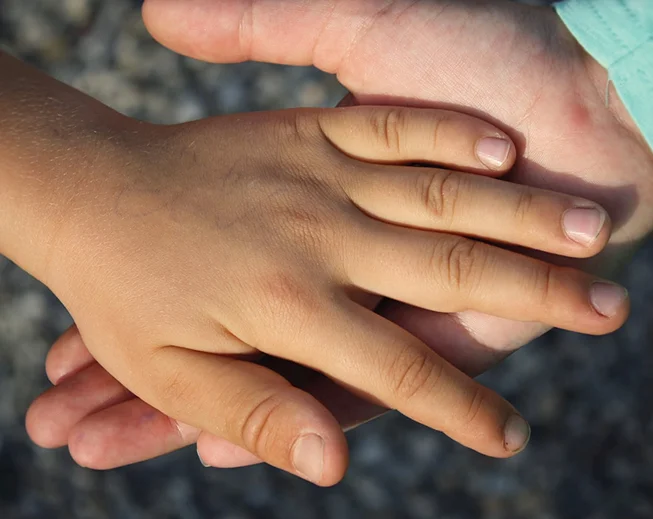 An adult’s hand cradling a child’s hand