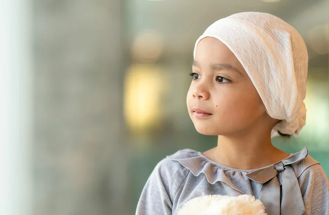 A young girl in a headscarf undergoing cancer treatment