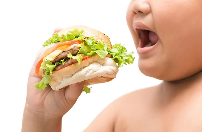 A child biting into an oversized burger